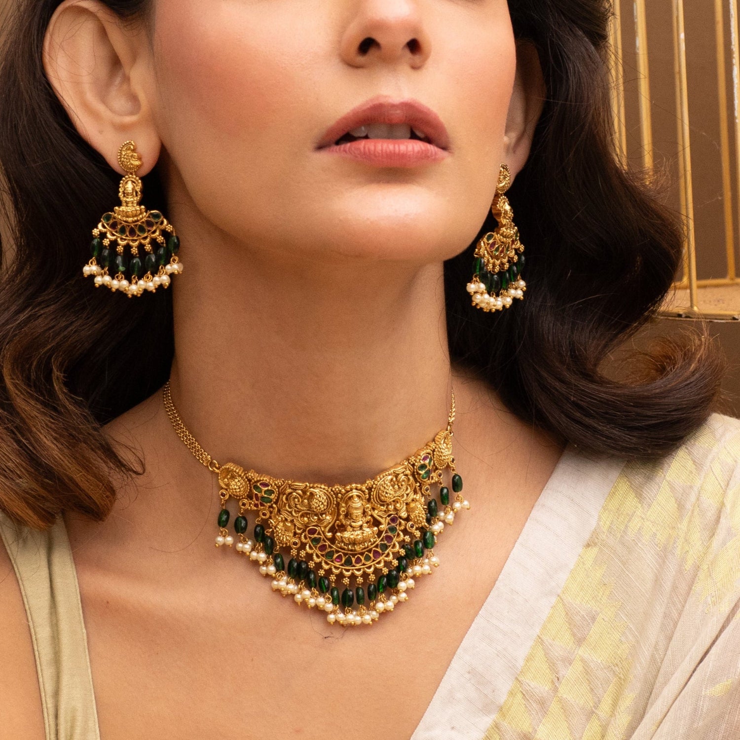 A picture of Indian artificial jewelry. It is an antique gold plated choker with green beads, divine Laxmi pendant and peacock motifs.