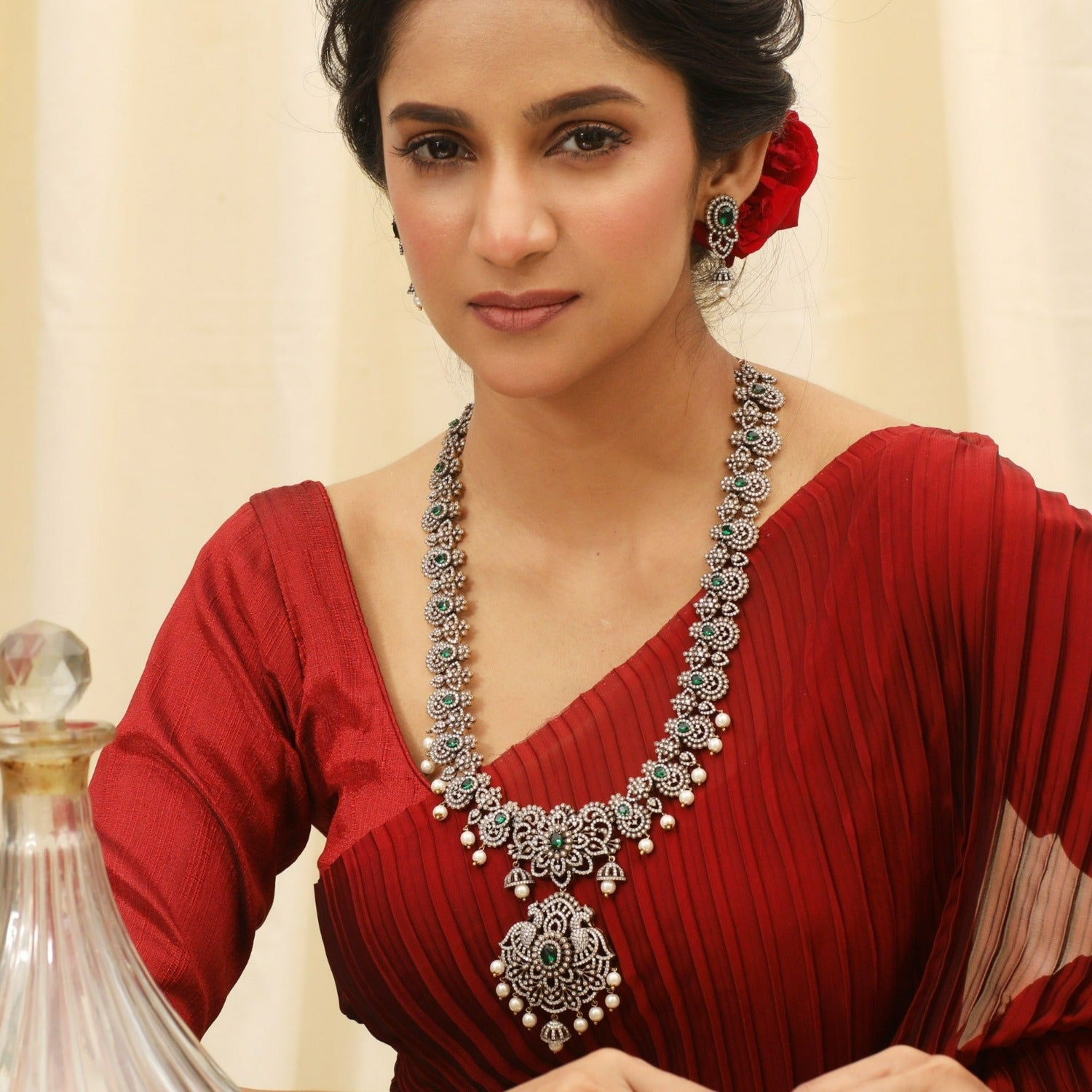 A picture of an Indian artificial jewelry set: an antique plated necklace and earrings set with green gemstones and Cubic Zirconia on a white background.