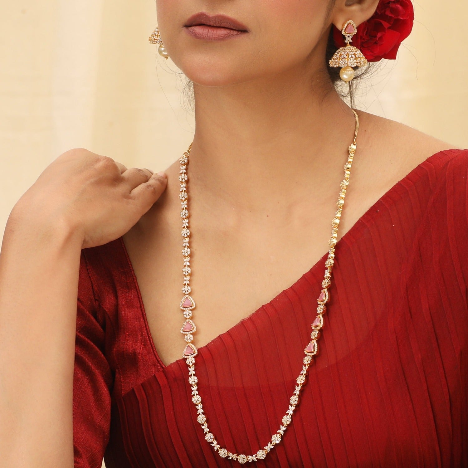 A picture of an Indian artificial jewelry set with a gold-toned necklace and matching earrings, featuring Cubic Zirconia and green stones.